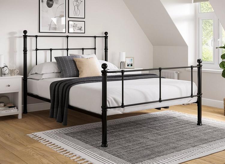 Traditional black metal bed frame with tall headboard and foot end, styled in a light neutral bedroom.