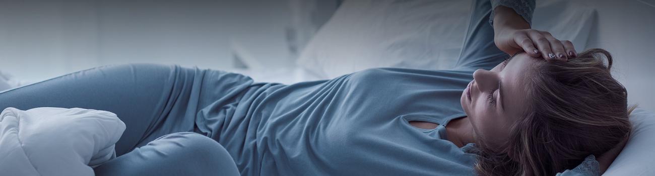 woman in bed in the background with an alarm clock in the foreground